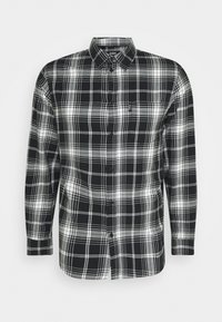 Camicia a maniche lunghe a quadri in bianco e nero con colletto button-down, caratterizzata da check patterns di diverse dimensioni e una singola tasca sul petto.