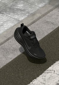 Svart Nike löparskor med texturerad tyg, rundad form, snörningsdesign och en Zoom Air dämpningslogotyp på sidan.