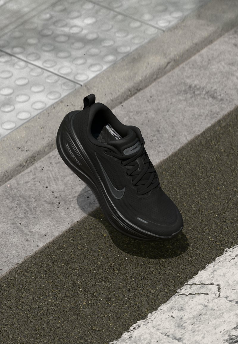Svart Nike löparskor med texturerad tyg, rundad form, snörningsdesign och en Zoom Air dämpningslogotyp på sidan.