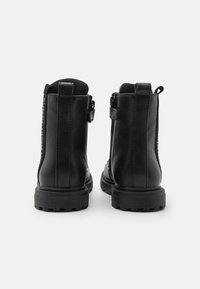 Czarne skórzane botki za kostkę o teksturowanym wykończeniu, okrągłym nosku, gumowej podeszwie i bocznych zamkach błyskawicznych dla łatwego zakładania. Z tyłu znajduje się pętelka do zaciągania.