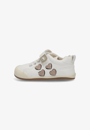 Zapatillas blancas para niño pequeño con suela beige, cuatro parches brillantes en forma de corazón y una correa de Velcro con un ícono de huella.