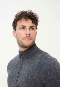 Grauer Zip-up-Pullover mit hohem Kragen, aus strukturiertem Material, das durchgehend kleine Einschlüsse in helleren Farben aufweist. Einfaches Design ohne zusätzliche Muster.