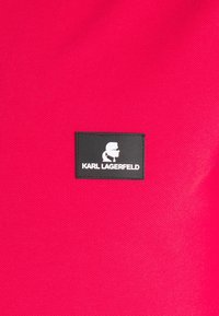 Pink fabric tote featuring a textured finish and a prominent black leather label with white logo reading "KARL LAGERFELD."