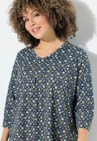 Tunic blu con motivo geometrico caratterizzato da diamanti e quadrati, scollo a V e maniche a tre quarti, realizzato in tessuto morbido.