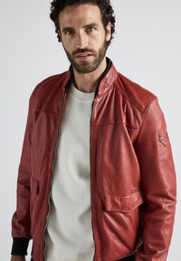 Rød læder bomberjakke med lynlås fortil, sidelommer og ribbede manchetter. Casual design med en glat tekstur og subtile syninger.