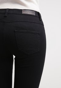 Černé džíny z denimu se slim fit střih, designem zadních kapes a značkovou koženou nášivkou na pase. Hladká textura a klasický styl.