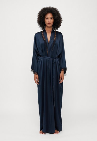 Robe en satin navy avec dentelle au niveau du col et des manches, dotée d'une taille à lien et d'une silhouette longue et fluide. Texture lisse, design minimal.