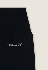 Leggings neri realizzati in materiale elasticizzato, caratterizzati da un'alta vita e un piccolo logo argentato "FREDDY" sul lato sinistro frontale.