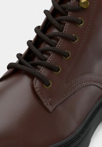 Braune Leder-Schnürschuhe mit dunkelbraunen Schn�ürsenkeln und goldenen Ösen. Mit abrundeter Zehenpartie und strukturiertem Gummisohle.