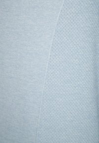 Helles blaues Sportgewebe mit einem glatten Abschnitt und einem strukturierten, durchlässigen Detail. Weiches, atmungsaktives Material, das sich für Sportbekleidung eignet.