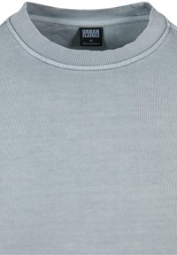 Světle šedá mikina s žebrovaným kulatým výstřihem a texturovanou látkou. Obsahuje vnitřní etiketu s údaji o velikosti a původu.