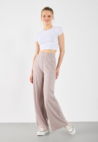 Lys grå, ribbede vide bukser med høy midje. Stylet med en tettsittende hvit crop top og beige plattform sneakers.