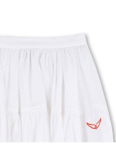 Λευκή φούστα με έκταση, φτιαγμένη από υφασμάτινη υφή με διακριτικό σχέδιο από κουκκίδες, διαθέτει ρυθμισμένα τμήματα και πορτοκαλί κεντητό διακοσμητικό στη βάση.