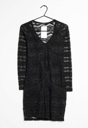 Black lace dress with a V-neck, long sleeves, and textured zigzag pattern. Features fringed accents along the front panels. Hangs from a hook.