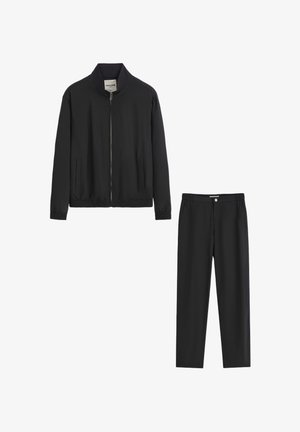 Veste noire zippée avec col montant et poignets élastiques, associée à un pantalon à taille élastique assorti, les deux présentant une texture lisse.