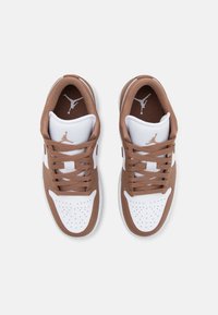 Brune og hvite joggesko med en glatt lær- og mesh-overdel, med runde lisser og perforert tå, merket med en grå logo.