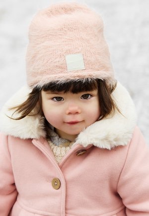 Pink wool coat with faux fur trim, brown buttons, and a matching fluffy pink hat. The layered sweater underneath is light gray with a knit texture.