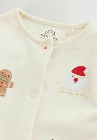 Cremfarbenes Baby-Body mit Druckknöpfen, besticktem Santa-Gesicht, Lebkuchenmann und dem Text "Santa Baby" in der Nähe des Kragens.