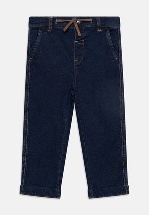 Mørkeblå denimbukser med snøring i midjen, to frontlommer og oppbrettede ermer med kontrasterende sømdetaljer.