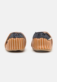 Gestreifte orange-weiße Stoffschuhe mit weichen grauen Akzenten, runder Form, zum Hineinschlüpfen und flexiblen beigefarbenen Sohlen.