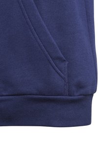 La tela de sudadera azul marino presenta una textura suave con un bolsillo tipo canguro y bajo acanalado, mostrando un diseño simple y casual.