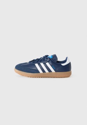 Scarpa sportiva blu navy con strisce bianche, parte superiore in suede e pelle, suola in gomma naturale e un'etichetta blu con il logo del marchio sulla linguetta.