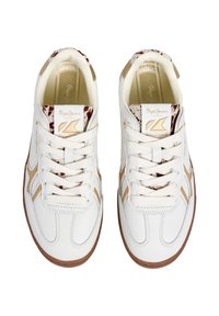 Baskets blanches au design texturé, avec des accents beige et un textile à motifs au talon, fermeture à lacets et semelle en caoutchouc.