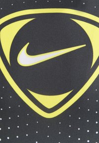 Czarna tkanina z dużym, żółto-białym logo Nike. Projekt przedstawia trójkątny kształt oraz małe białe kropki na tle.
