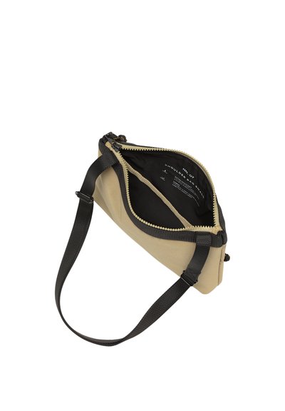 Sac à bandoulière beige avec sangle noire ajustable, fermeture éclair ouverte révélant l'intérieur noir avec texte imprimé blanc à l'intérieur.