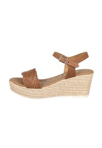 Sandalia cuña con parte superior de cuero trenzado marrón, tira ajustable en el tobillo y plataforma de yute trenzado. Plantilla de color marrón claro con marca en relieve.