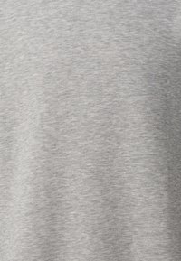 Szara tekstura tkaniny z widocznym wzorem dzianiny i delikatnymi poziomymi liniami, ukazująca naturalne fałdy i niewielkie różnice w odcieniu.