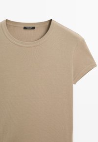 Beige katoenen t-shirt met een ronde halslijn en korte mouwen. Gladde textuur, geribbelde kraag en een subtiele merklabel genaaid aan de binnenkant.