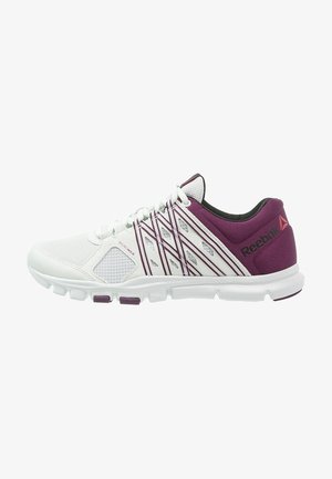 Zapatilla deportiva Reebok blanca y púrpura con parte superior de malla, patrones laterales geométricos y suela acolchada, vista de lado.