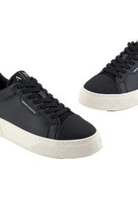 Sneaker in pelle nera con punta testurizzata e lati in rete, dotati di una suola platform bianca e marchio "Armani Exchange" sul lato.