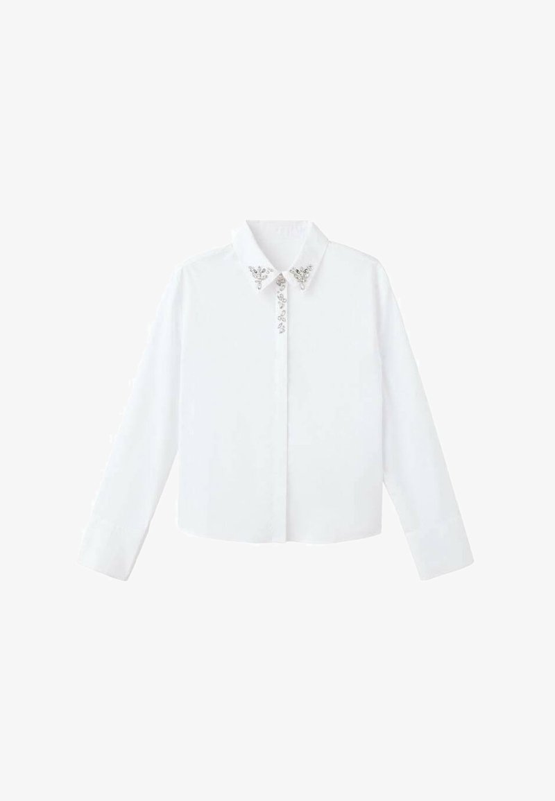 Camicia bianca a maniche lunghe con colletto, caratterizzata da decorazioni argentate vicino al collo e una vestibilità dritta e su misura. Tessuto dalla consistenza liscia.