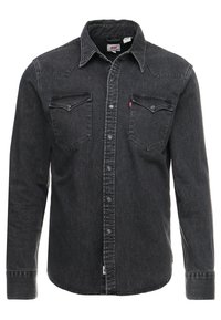 Camicia di jeans nera con bottoni, maniche lunghe, due tasche sul petto, spalla a punta e cuciture a contrasto. Presenta una texture morbida e una vestibilità classica.