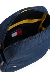 Borsa zip in nylon blu navy con esterno testurizzato; fodera gialla all'interno e logo del marchio visibile in basso.