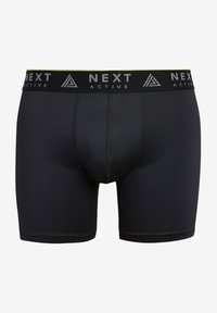 Pantaloni corti attivi neri con design semplice. Presentano una cintura elastica di colore grigio e verde con l'etichetta "NEXT ACTIVE". Realizzati in tessuto elasticizzato.