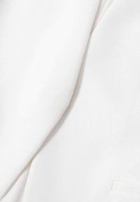 Tissu blanc, texture lisse, légèrement froissé, avec des détails de couture visibles. Le matériau semble léger et respirant.