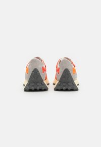 Sneaker aus Wildleder und Textil mit grauem Obermaterial und orangefarbenen Akzenten, schwarzer Gummisohle und einem dreieckigen Fersen-Design.