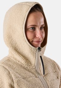 Fleece hoodie in crème met een gestructureerd oppervlak, voorzien van een volledige rits, contrasterende voering en platte naden voor duurzaamheid.