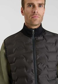 Gilet imbottito nero con colletto alto, chiusura a zip e maniche verdi testurizzate con motivo geometrico.