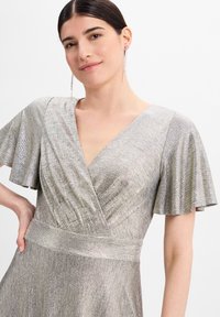 Silbernes, metallisches Kleid mit V-Ausschnitt und schwingenden Ärmeln. Strukturierter Stoff mit taillierter Passform, der in einen ausgestellten Rock übergeht.