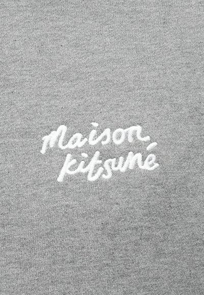 Halli hall, millel on valgest kaldkirjas tekst "maison kitsuné". Pehme kangas sileda tekstuuriga.
