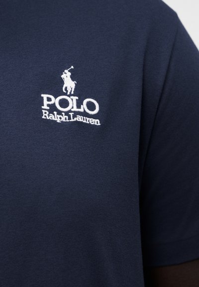 Marineblaues Hemd mit weiß gesticktem Polo Ralph Lauren Logo, das auf der Brust einen Polospieler zu Pferd zeigt.