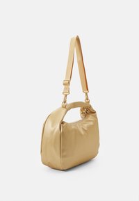 Glatt beige skuldertaske med justerbar rem, blødt stofkrop og rund top-håndtag, præsenteret mod en hvid baggrund.