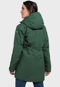 Green, insulated jacket with a hood, cinched waist, and visible logo. Smooth texture and shoulder seams, designed for warmth and comfort.