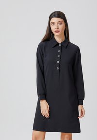 Robe noire à col avec manches longues, dotée d'une patte de boutonnage et de poignets élastiques, fabriquée dans un tissu lisse au design simple.
