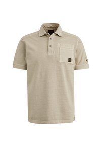 Polo shirt beige à manches courtes fabriqué en tissu doux, avec un col à boutons, une poche sur la poitrine et une petite étiquette logo sur la manche.