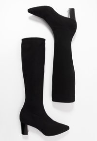 Bottes noires montantes avec un bout pointu et un talon bloc. Fabriquées dans un matériau lisse et extensible, avec un design épuré et sans quincailles visibles.